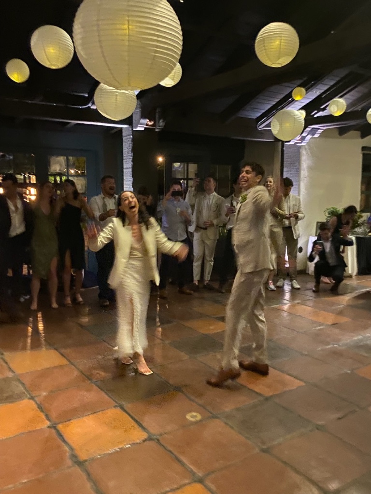 A couple laughing on the dance floor under paper lanterns