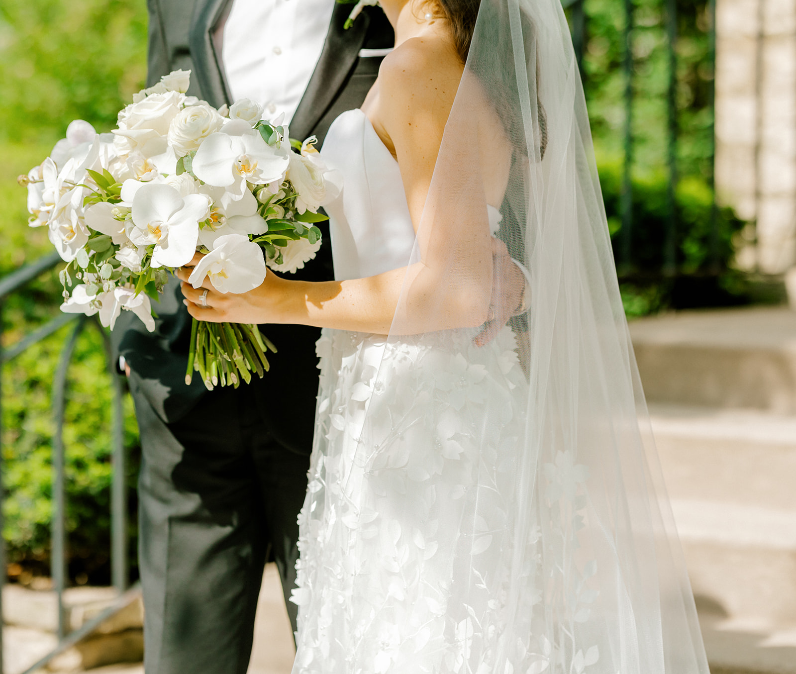 A bride holding a white orchid bouquet beside her partner